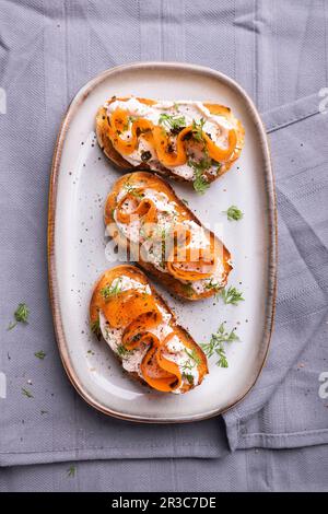 Fette di baguette tostate con crema di mandorle, salmone alla carota vegana e aneto Foto Stock