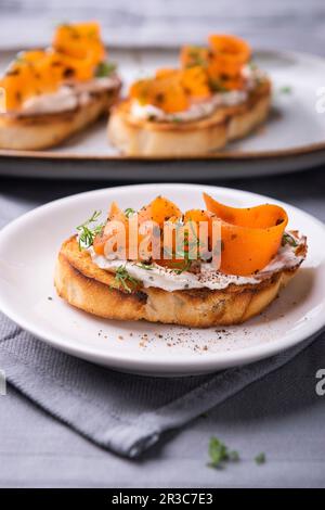 Fette di baguette grigliate con crema di mandorle, salmone alla carota vegana e aneto Foto Stock