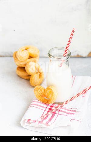 Biscotti a spirale per pasta sfoglia tradizionale conosciuti come orecchie di maiale su piatto con zucchero Foto Stock