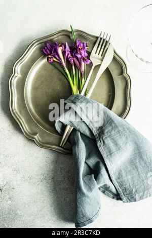Primavera ambiente floreale tavolo decorato con fiori viola iris selvaggio su tavola di cemento Foto Stock
