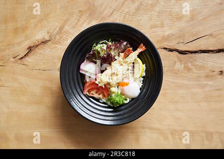 Ramen con tagliatelle di udon, insalata, uova, gamberi tempura e cipolla Foto Stock