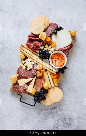 Tagliere di formaggi con cracker, salumi, grissini, uva e albicocche secche Foto Stock