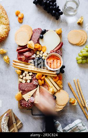 Tagliere di formaggi con cracker, salumi, grissini, uva e albicocche secche Foto Stock