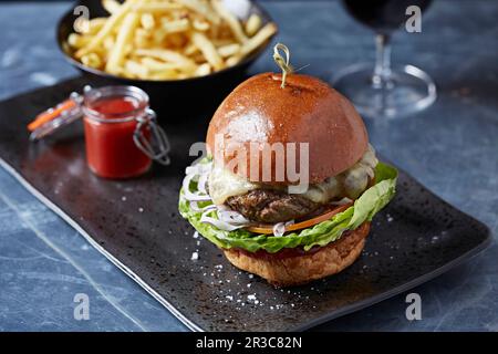 Hamburger di formaggio in un panino brioche con patatine fritte Foto Stock