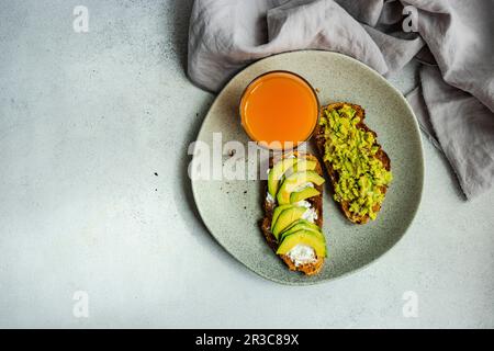 Colazione sana con toast all'avocado su un tavolo di cemento Foto Stock