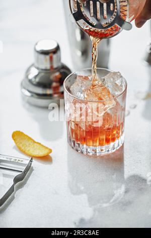 Un cocktail vecchio stile che viene versato in un bicchiere Foto Stock