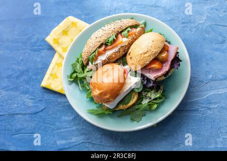 Panini con brie, salmone affumicato e prosciutto sulle foglie di lattuga Foto Stock