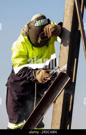 Uomo di metallo di saldatura su di un sito in costruzione, Tradesman lavora con la torcia di saldatura Foto Stock