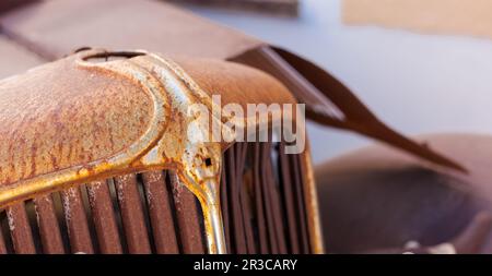 Griglia anteriore di un vecchio arrugginito autovettura in un cantiere di scarto Foto Stock