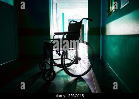 Sagoma della sedia a rotelle vuota parcheggiata nel corridoio dell'ospedale Foto Stock