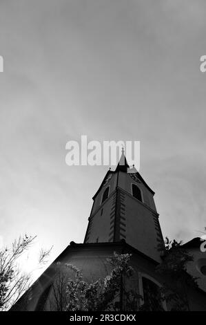 Una struttura torreggiante in cima ad una chiesa, spesso adornata con dettagli architettonici e una campana, che serve come un punto di riferimento prominente in una comunità. Foto Stock