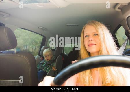 Il ragazzino è seduto in un posto auto ride con la mamma Foto Stock