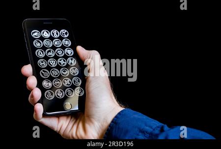 Mano maschio caucasica che tiene un telefono cellulare con icone di criptovaluta sullo schermo Foto Stock
