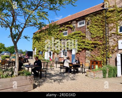 Snape Maltings, Suffolk, Regno Unito - 23 Maggio 2023: Posti a sedere all'esterno al Malt Cafe. Foto Stock