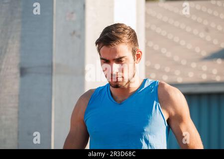 Giovane atleta caucasico focalizzato e professionale pronto per la corsa in sprint in posizione di partenza Foto Stock