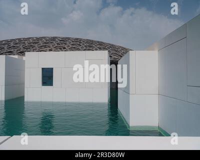 Abu Dhabi, Emirati Arabi Uniti - 21 marzo 2023 : esterno del Louvre, famoso museo di Abu Dhabi. Pareti bianche semplici che circondano un fossato verde smeraldo sormontato da un ornato Foto Stock