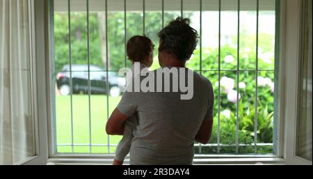 Bambino e nonno accanto alla finestra durante il giorno piovoso Foto Stock