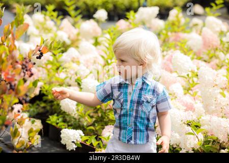 Bel ragazzo biondo all'aperto nel giardino botanico Foto Stock