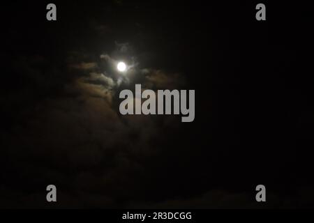 la luna splende tra le nuvole nel cielo notturno. Luna piena nel cielo Foto Stock