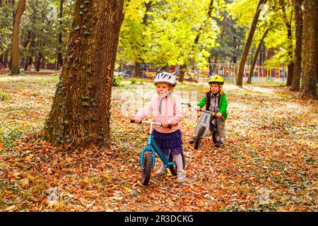 Allegri bambini in età prescolare all'aperto su bici Balance Foto Stock