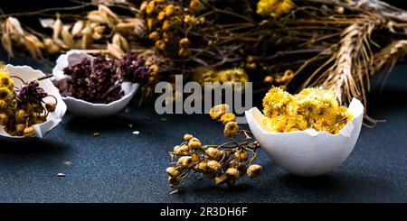 Decorazioni di Pasqua alla moda. Uova organiche spaccate con erba secca e fiori secchi sul piatto. Piuma d'uccello. Spazio di copia. Biglietto d'auguri Foto Stock