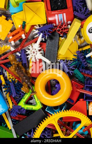 Un'abbondanza di giocattoli nella stanza dei bambini, molte parti multicolore di plastica dai progettisti, parti di ricambio per giocattoli, figurine e cubi. Foto Stock