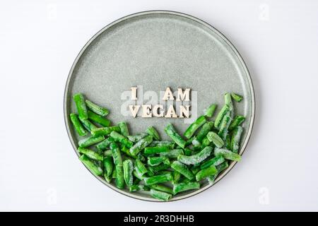 Sono UN testo VEGANO in targa. Veganismo, stile di vita sano vegetariano. Sano mangiare vegan, fagiolini Foto Stock