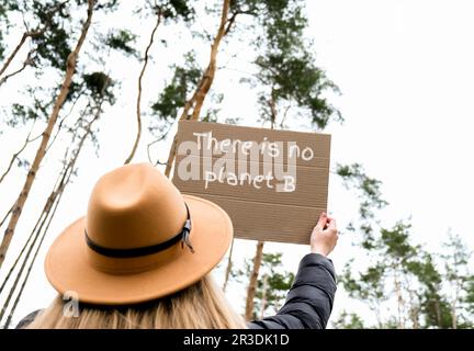 Mani femminili che tengono il cartone con il testo NON C'È NESSUN PIANETA B all'esterno. Natura sfondo. Attivista protettore Foto Stock