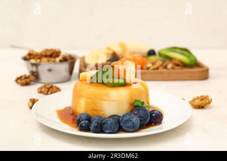 Delizioso budino con frutta e mirtilli ricoperti di sciroppo di caramello su tavolo bianco Foto Stock