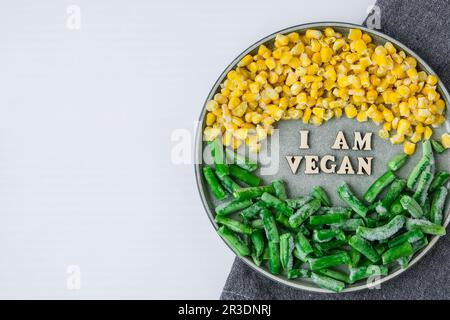 Sono UN testo VEGANO in targa. Veganismo, stile di vita sano vegetariano. Sano mangiare vegan, fagioli verdi mais giallo Foto Stock