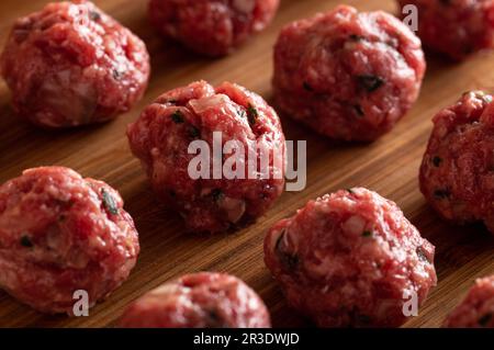 Polpette crude non cotte sul tagliere di legno. Foto Stock