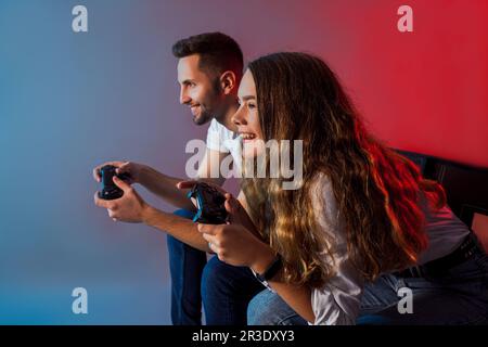 Amici felici che tengono i joystick e iniziano il gioco virtuale Foto Stock