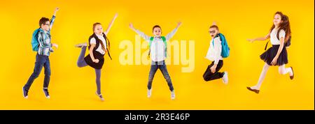 L'insieme dei bambini della scuola differenti stanno saltando e agitando le loro mani Foto Stock