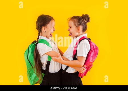 Due studentesse sorridenti in uniforme stanno abbracciando il giallo Foto Stock