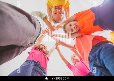 La squadra di ragazzi e ragazze si accatastano le mani Foto Stock