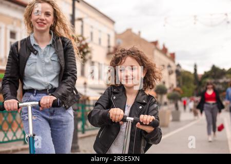 L'elegante bambina guida uno scooter in città Foto Stock