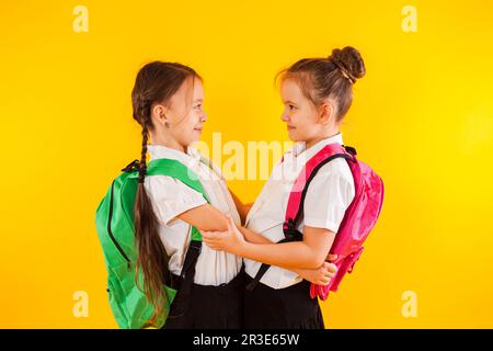 Due studentesse sorridenti in uniforme stanno abbracciando il giallo Foto Stock