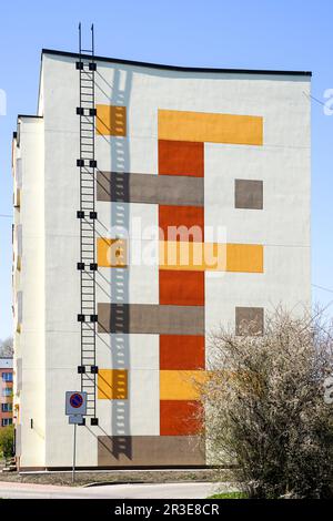 Edificio di appartamenti a più piani, rinnovato e isolato termicamente, con scale di fuga dal fuoco su uno sfondo blu cielo Foto Stock