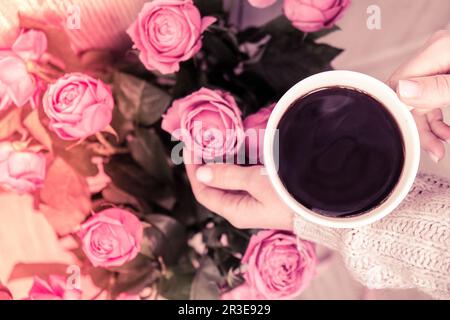 Tazza di caffè e rose rosa. Concetto di vacanza, bouquet di rose per un compleanno, bouquet di fiori al mattino prima colazione. FEM Foto Stock