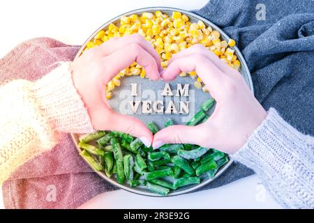 Mani femminili a forma di cuore amore sono VEGAN testo in piastra. Veganismo, stile di vita sano vegetariano. Sana alimentazione vegana, grea Foto Stock