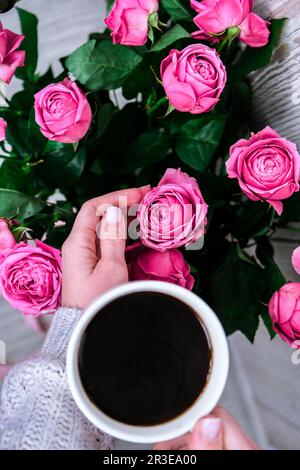 Tazza di caffè e rose rosa. Concetto di vacanza, bouquet di rose per un compleanno, bouquet di fiori al mattino prima colazione. FEM Foto Stock