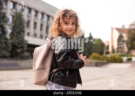 La bambina cammina per la città con una borsa Foto Stock