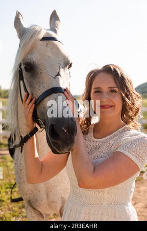 Ritratto di una giovane donna in un vestito che abbraccia il cavallo Foto Stock