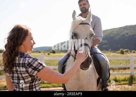 La giovane coppia sta riposando in un allevamento di cavalli Foto Stock