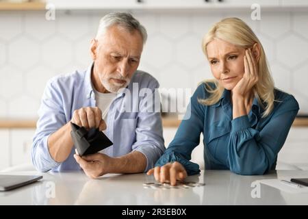 Famiglia problemi finanziari. Rovesciato Senior Couple contando le monete rimanenti in cucina Foto Stock