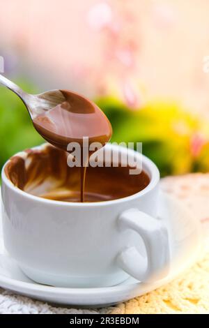 Tazza di cioccolata calda sul tavolo al bar all'aperto in estate. Caffè e colazione al ristorante. Cioccolato, latte caldo schiumato, cacao. Foto Stock