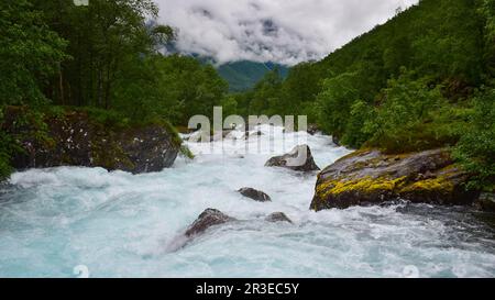 Rocce bagnate da forti rapide del fiume acqua, nuvole che avvolge le montagne nella nebbia, pioggia giornata estiva a Trollstigen, Norvegia, Scandinavia, Europa Foto Stock