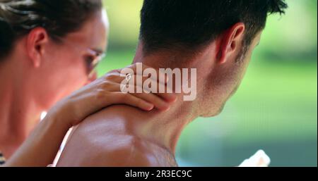 Moglie che applica la crema solare al corpo del marito. Donna strofinando crema solare per la pelle partner Foto Stock