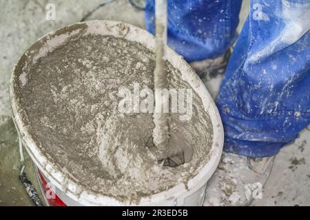 Malta pasta di cemento, principalmente asciutto, mescolato in secchio a casa cantiere, primo piano particolare da sopra Foto Stock