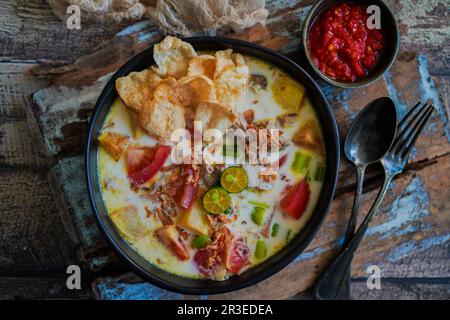 Soto Betawi è una zuppa indonesiana fatta di latte di cocco e riempita di manzo, patate e pomodori Foto Stock